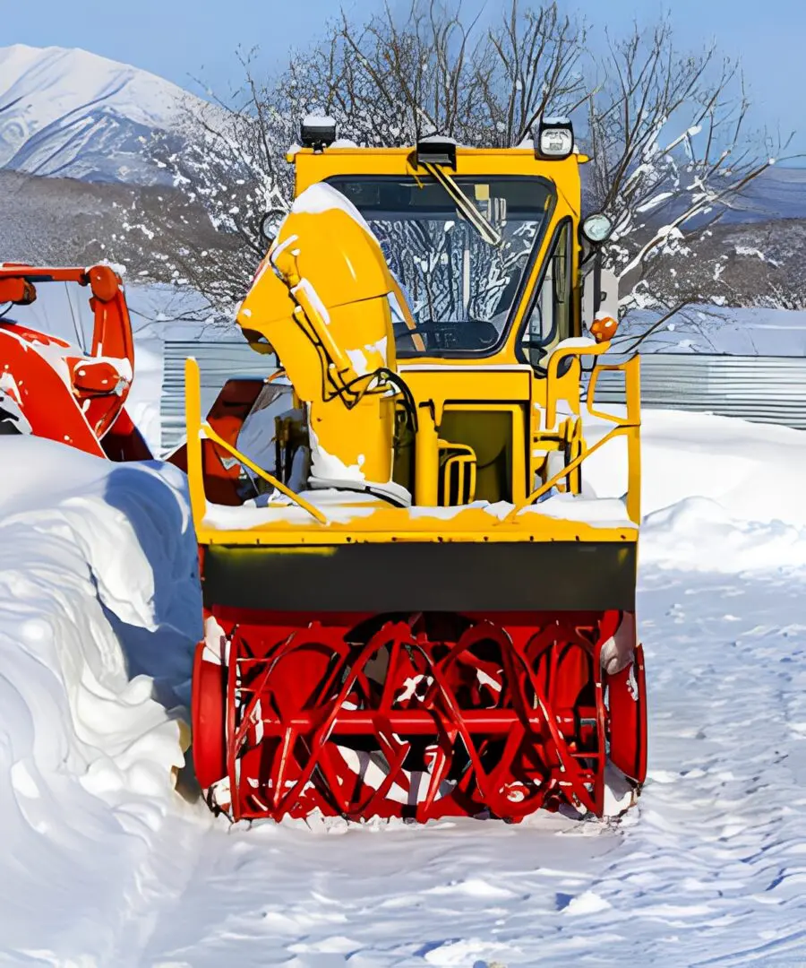 Yellow snowplow clearing snowy path.
