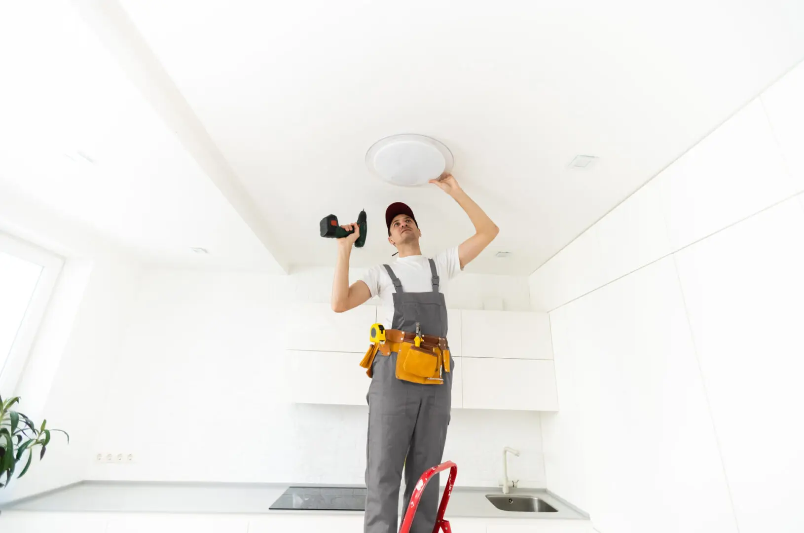 Electrician installs a chandelier on the ceiling. Construction concept.
